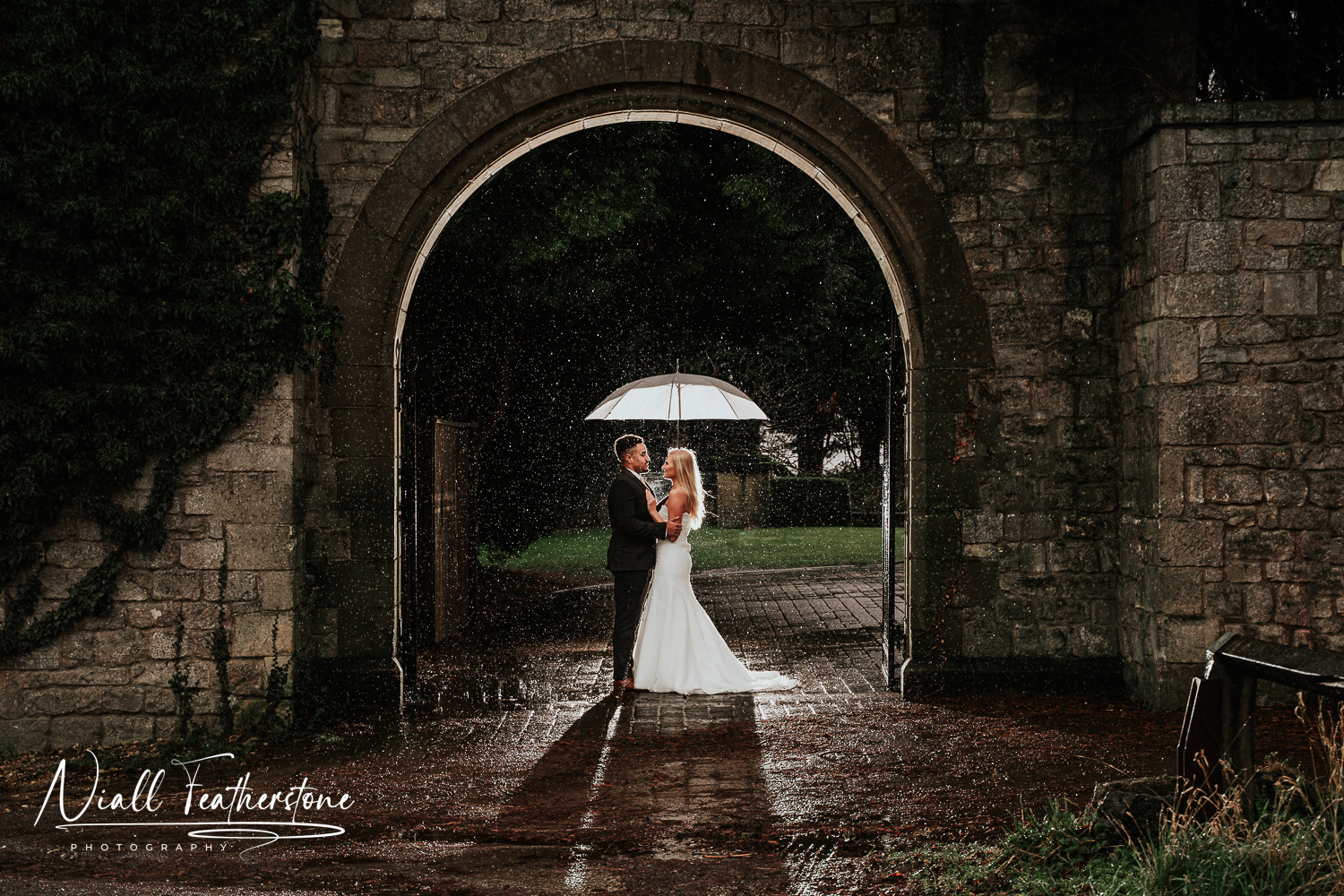 Bride and Groom Cuddle under umbrella in the rain at Hazlewood Castle West Yorkshire