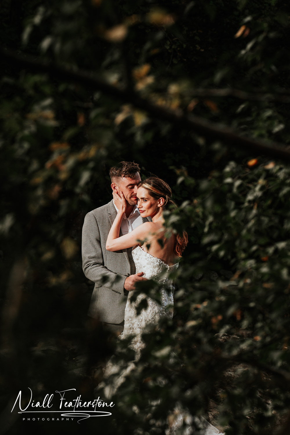 Couple posed cuddling and photo through trees for a unique photograph