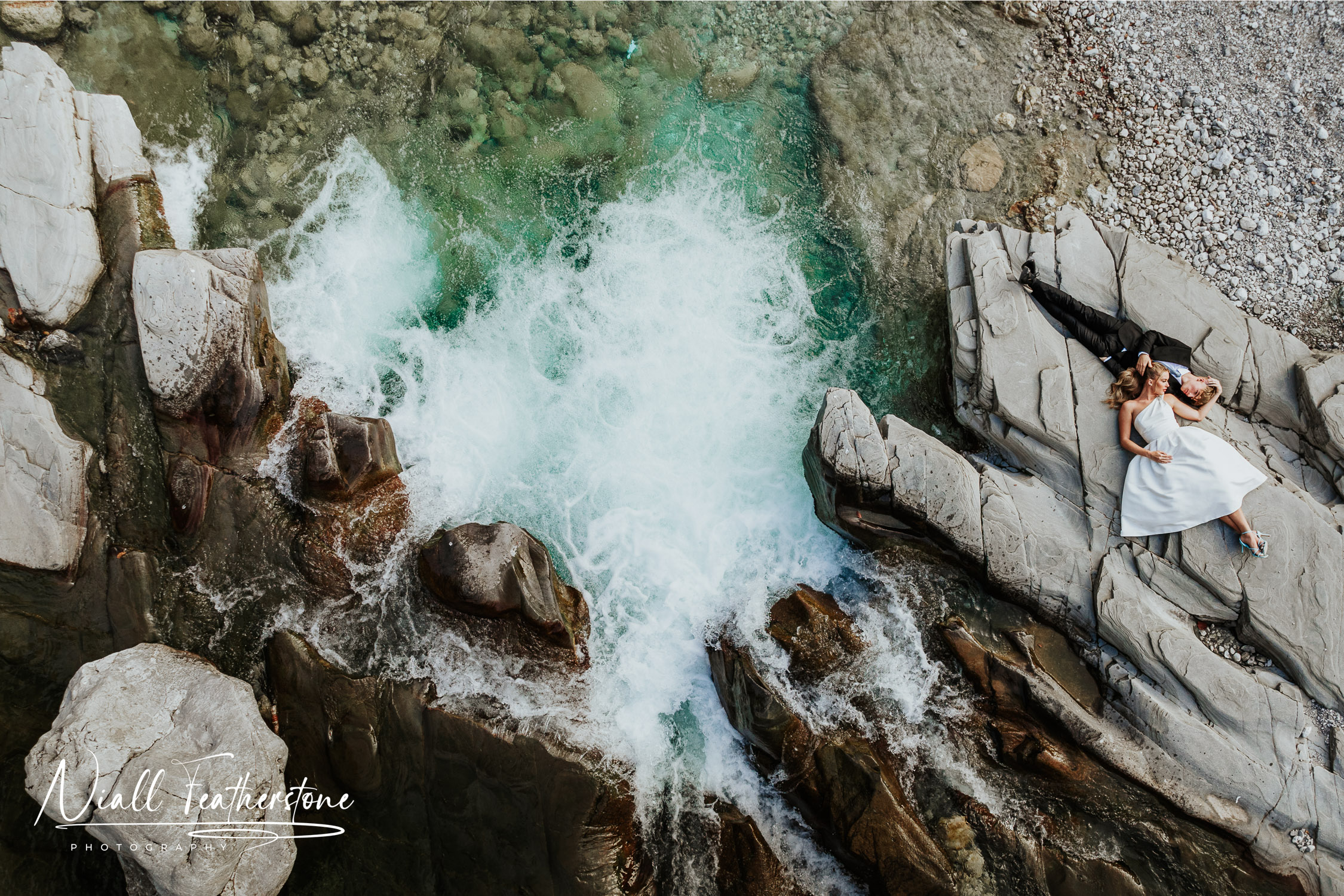 Wedding Couple Lying on Rocks by Waterfall in Italy captured by Drone